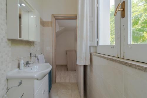 een witte badkamer met een wastafel en een raam bij Appartamento con vista piscina in Noto