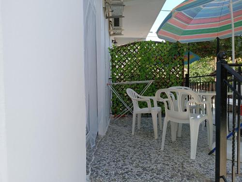 a patio with a table and chairs and an umbrella at Niki Seaside Apartments in Platamonas