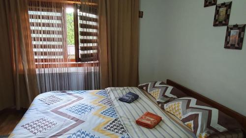a bed with a quilt on it with a window at Cazare la fermă in Galeşu