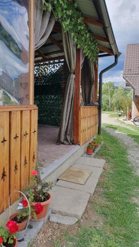 a house with a porch with flowers in pots at Cazare la fermă in Galeşu