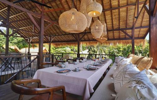 una mesa de comedor larga con mantel y sillas blancas en Hani Hideaway en Gili Air