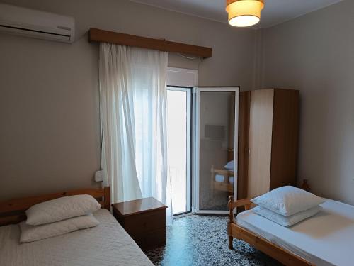 a bedroom with two beds and a sliding glass door at Niki Seaside Apartments in Platamonas