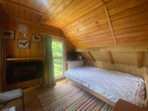 um quarto num chalé de madeira com uma cama e uma janela em Vila Mara Busteni em Buşteni
