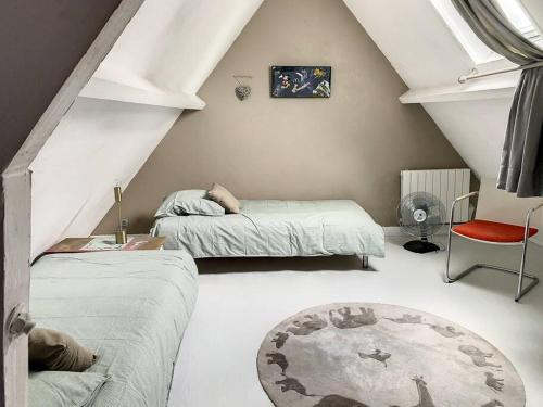 a attic room with two beds and a red chair at Le Odette - Campagne chic in Jaux