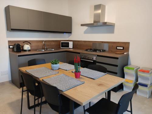 una cucina con tavolo in legno con sedie e una cucina con piano cottura di La Stazione a Monserrato