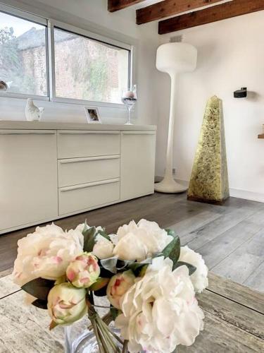 a vase filled with white flowers in a room at Le Odette - Campagne chic in Jaux