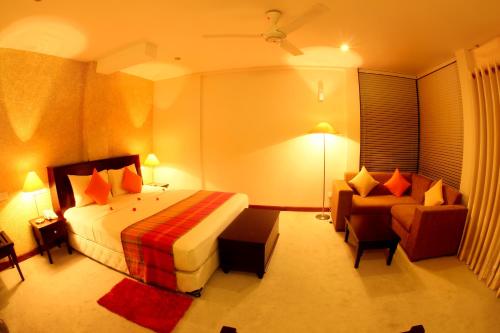 a hotel room with a bed and a couch at Opulent River Face Hotel in Colombo
