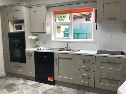 a kitchen with white cabinets and a sink and a window at Paddy Mac's Self Catering Holiday Bar in Drumshanbo