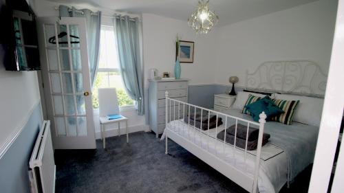 een slaapkamer met een wit bed en een kroonluchter bij The White Lion at Wicken in Milton Keynes