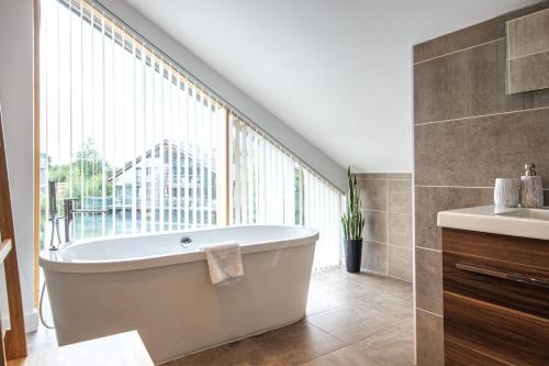 baño con bañera, lavabo y ventana en Waters Edge 15, Kingsholm P en South Cerney