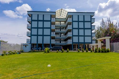 a large building with a grassy yard in front of it at Ebony Batian Nanyuki 1bedroom in Nanyuki