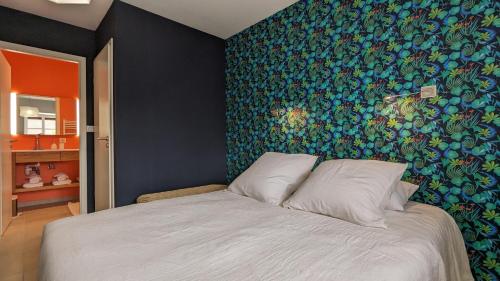 a bedroom with a large bed with a colorful wall at L'orcheran in Vielverge