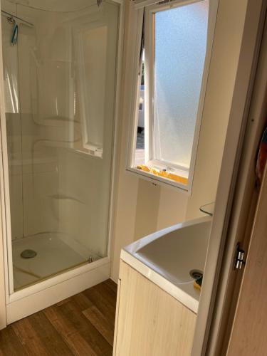 uma casa de banho com uma banheira e um chuveiro em vidro. em Mobil home 8 personnes camping l elysee em Le Grau-du-Roi