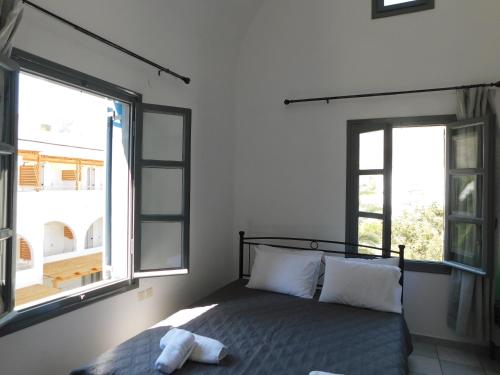 1 dormitorio con 1 cama y 2 ventanas en Perissa Art Villa - Kitchen & Washing Machine en Perissa