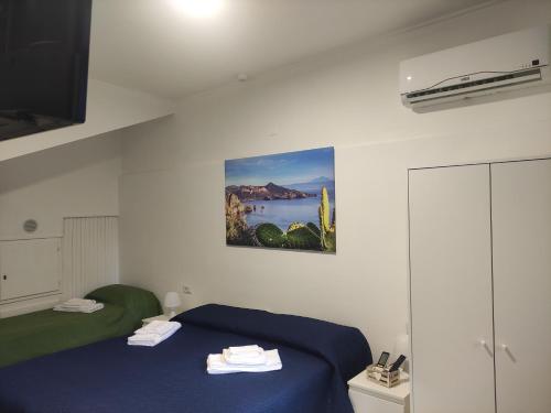 una camera con due letti e un dipinto sul muro di La Casetta di Elia a Città di Lipari