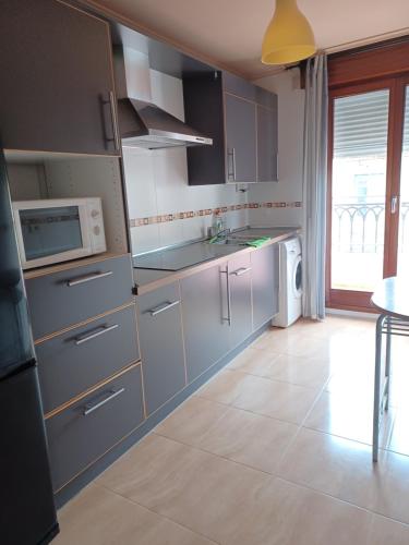 cocina con armarios de acero inoxidable y microondas en Ático duplex, en Santoña