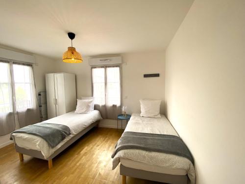 deux lits dans une chambre avec deux fenêtres dans l'établissement COCCON 2 By Dream Apartments, à Serris