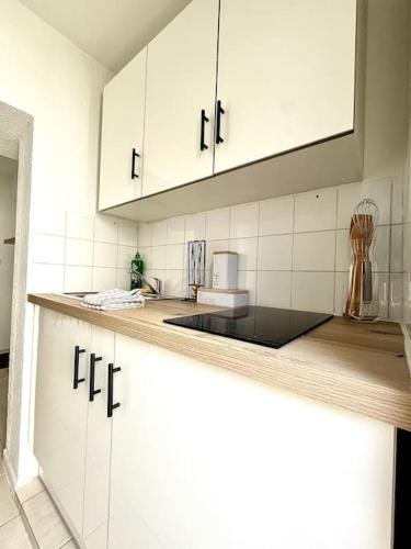 une cuisine avec des armoires blanches et un comptoir dans l'établissement La Topaze Bleue - Romans, à Romans-sur-Isère