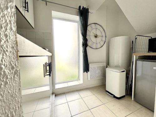 a kitchen with a refrigerator and a window with a clock at La Topaze Bleue - Romans in Romans-sur-Isère