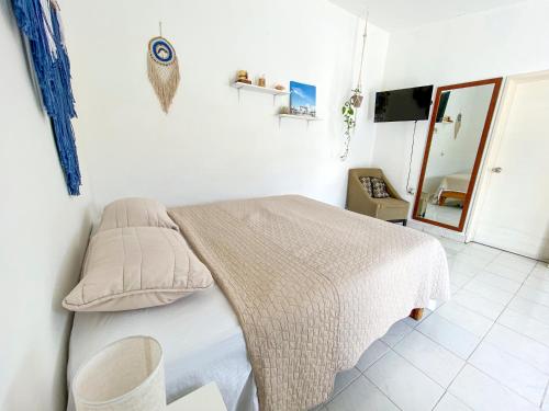 - une chambre blanche avec un lit et un miroir dans l'établissement Cómodo y bonito estudio en Cozumel, à Cozumel