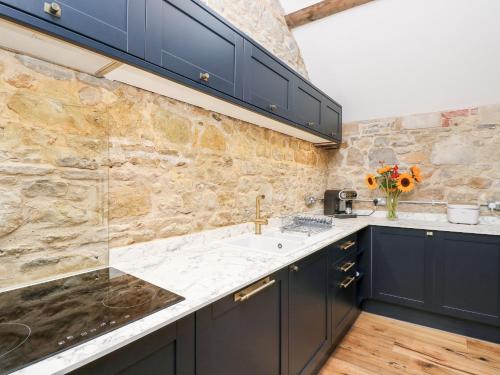 a kitchen with navy blue cabinets and a marble counter top at Tower Barn Cottage in Ryde