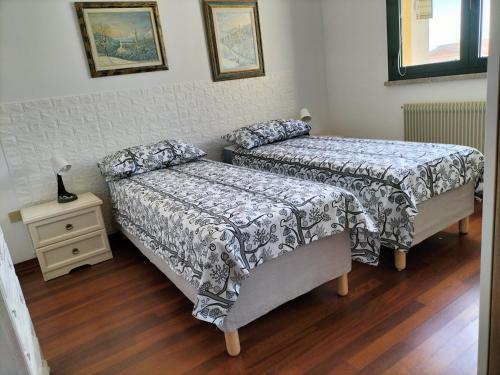 a bedroom with two beds and a night stand with a table at Finestre Verdi appartamento con parcheggio in Ronchi dei Legionari
