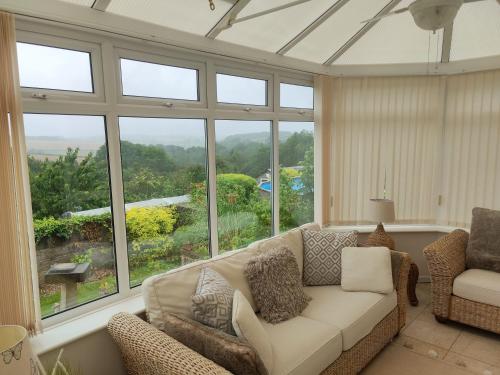 a living room with a couch and large windows at Stunning Views Peaceful Split Level Bungalow in Sutton in Ashfield