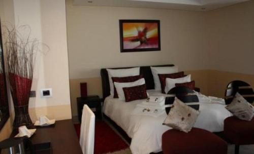una camera da letto con letto, lenzuola e cuscini bianchi di La Familia Vertigo Boutique Hotel a Windhoek