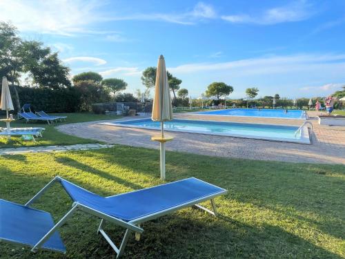 een paar stoelen en een parasol naast een zwembad bij Calilla Home-appartamento Scirocco in Grado