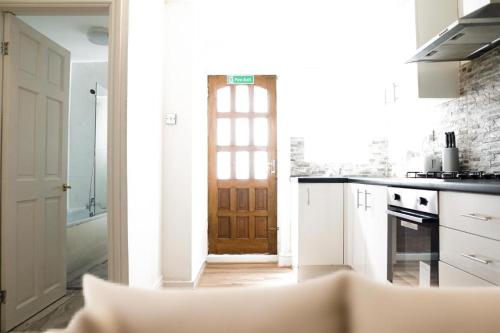 uma cozinha com uma porta que conduz a uma cozinha com armários brancos em Dally Private Bedroom Near to City Centre em Liverpool