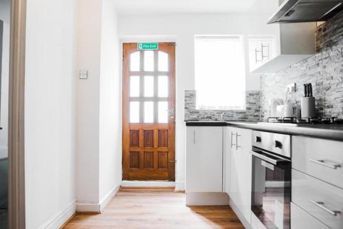 uma cozinha com armários brancos e uma porta de madeira em Dally Private Bedroom Near to City Centre em Liverpool
