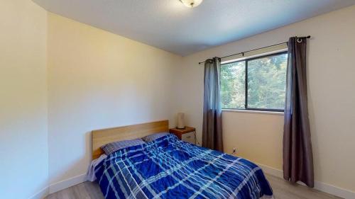 um quarto com uma cama azul e uma janela em Spacious 3 bedroom house em Gibsons