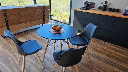 a table with four chairs and a bowl of fruit on it at Little Acre Luxury Pods in Tulbagh