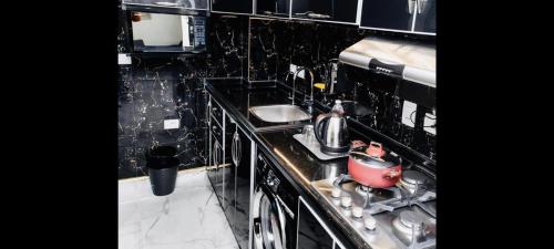 a black tiled kitchen with a stove and a sink at Port Said city, Damietta Port Said coastal road in Port Said