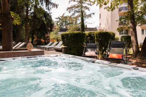 a hot tub in a yard with two chairs at Hôtel Diana Restaurant & Spa by HappyCulture in Molsheim
