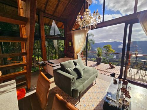 uma sala de estar com um lustre e uma cadeira verde em Cabanas Bougainville Hospedagem sofisticada em nova Petrópolis em Nova Petrópolis