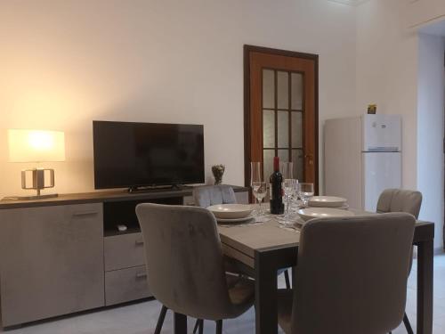a dining room with a table with chairs and a television at Le Case del Cortile in Catania