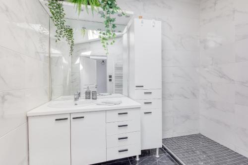 ein weißes Badezimmer mit einem Waschbecken und einem Spiegel in der Unterkunft Modern House 7min to Paris Professionals and Family in Alfortville