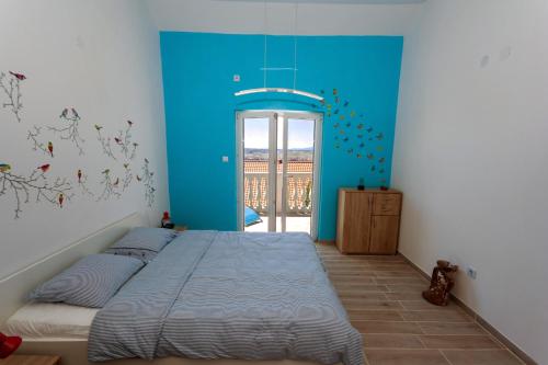 a bedroom with a bed with a blue wall at Apartment Mikuš in Stinica