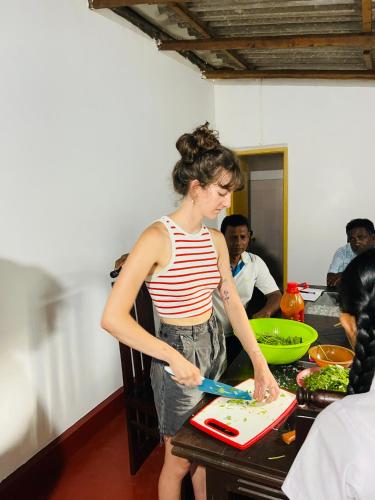 a woman standing in a kitchen preparing food on a cutting board at Geethani Tourist Home Polonnaruwa in Polonnaruwa