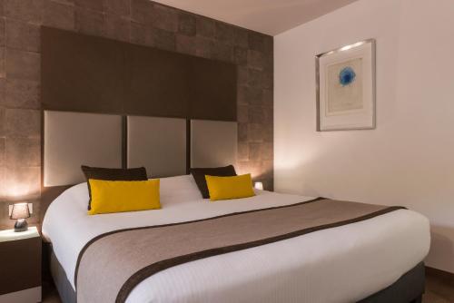 a bedroom with a large bed with yellow pillows at Hôtel Diana Restaurant & Spa by HappyCulture in Molsheim