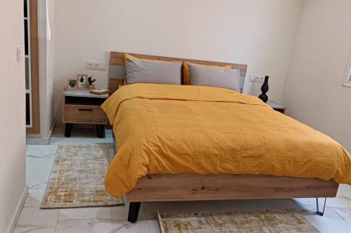 een slaapkamer met een bed met een geel dekbed en een bureau bij Belle maison avec jardin privatif in Casablanca