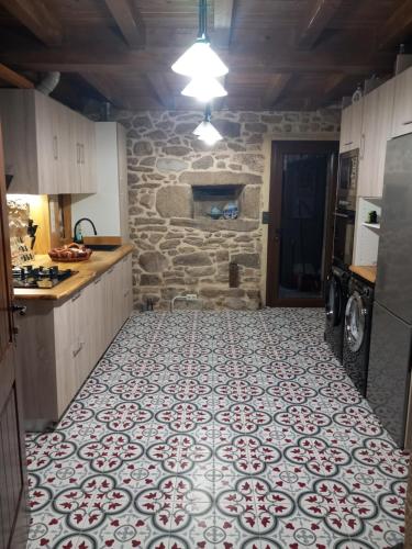 a kitchen with a tile floor and a stone wall at Casa de Crabera in A Coruña