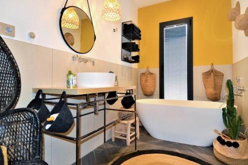 La salle de bains est pourvue d'une baignoire, d'un lavabo et d'un miroir. dans l'établissement La Villa aux Parasols, à Saint-Laurent-des-Arbres