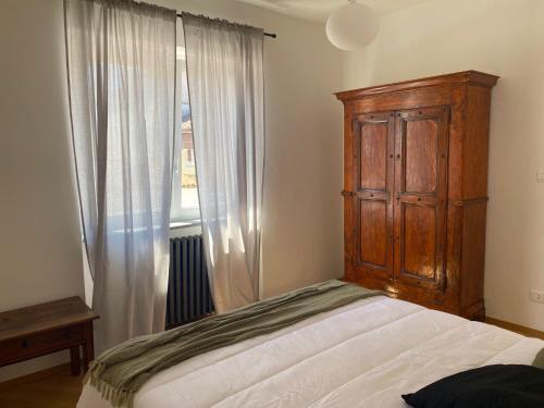 um quarto com uma cama com um armário de madeira e uma janela em La Casetta em Carrù