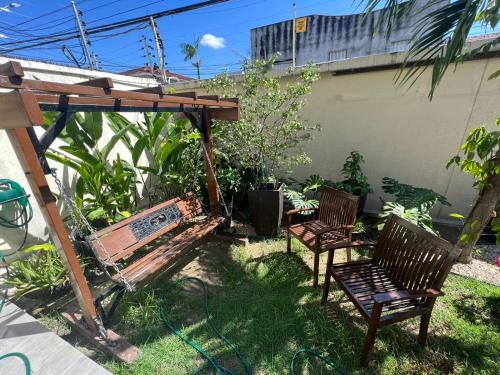 two chairs and a bench under a pergola at River X House in Manaus