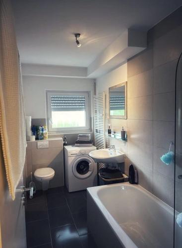 拉克斯道夫的住宿－Rückersdorf - IKON Immoleasing，浴室配有洗衣机、水槽和浴缸。