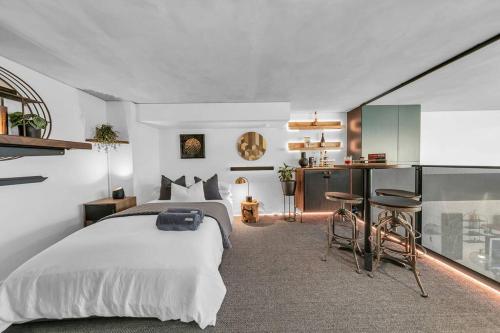 um quarto com uma cama e uma cozinha com um balcão em Sol Docklands - Unique 3 Bedroom Loft, Infinity Pool, Gym, Free Parking and Free Trams em Melbourne