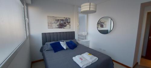 a bedroom with a bed with blue pillows and a mirror at Refugio Ballenas in Puerto Madryn