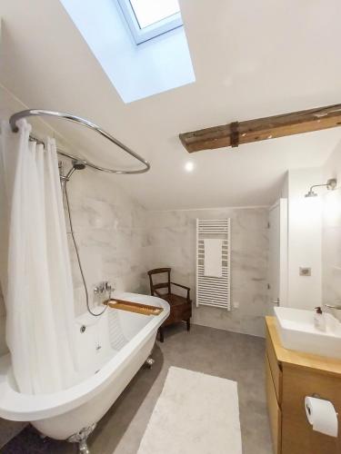 une salle de bain avec une baignoire blanche et un lavabo dans l'établissement Petit Est - Eco Cottage in large private garden near Saint-Emilion, à Blasimon